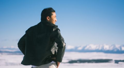 man looking toward horizon of snow white mountainous range