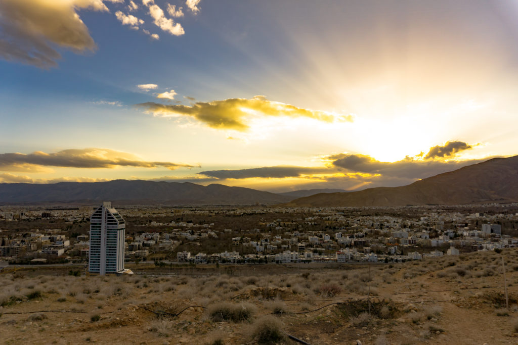 a sunset behind a mountain with a city view