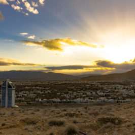 a sunset behind a mountain with a city view